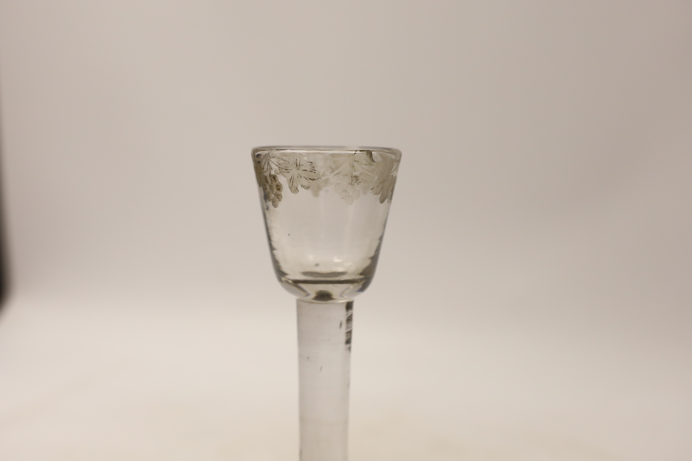 A George I or George II plain stem cordial glass, c.1720-30, with folded and domed foot and wheel engraved rim decorated with grape vines, 17.5cm